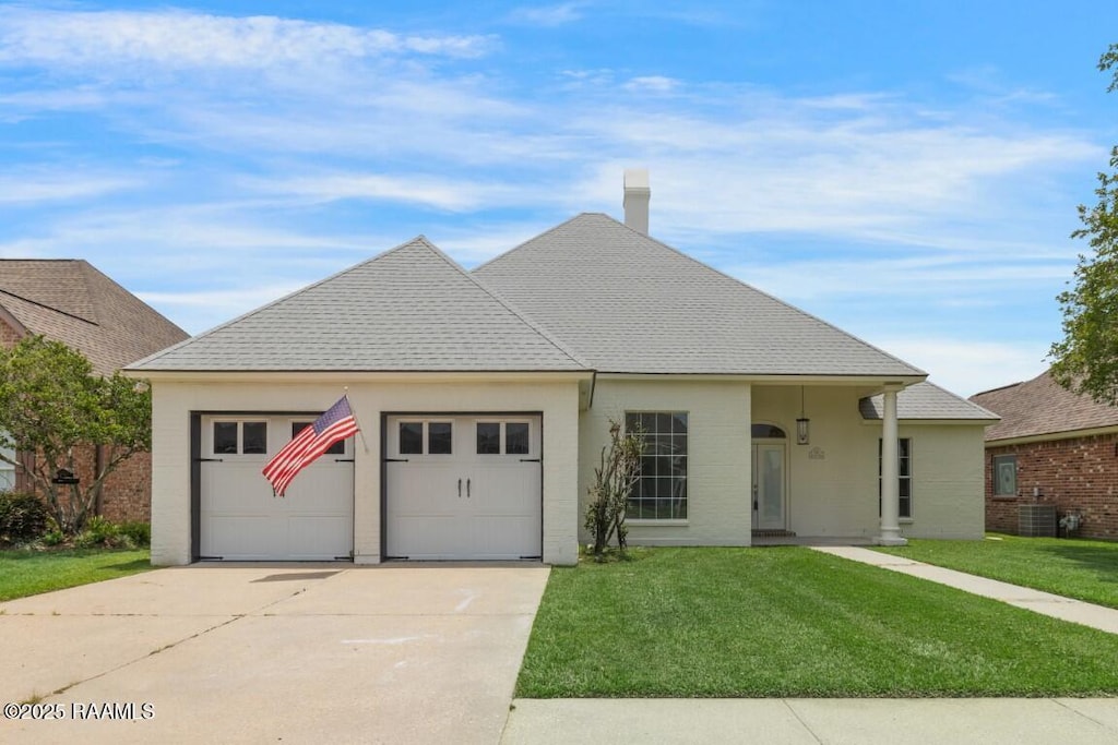 102 Bon Ami Dr, Lafayette, LA 70506 - view of front facade with concrete driveway, an attached garage, a front lawn, and brick siding