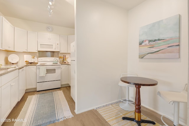 531 Silver St, New Iberia, LA 70560 - kitchen with white appliances, light wood-style flooring, white cabinetry, and light stone countertops