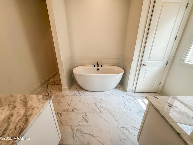 219 Timber Mill St, Lafayette, LA 70508 - bathroom with marble look tile flooring, a freestanding bath, vanity, and baseboards