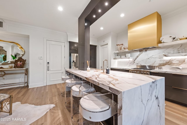 302 Richland Ave Unit 207C, Lafayette, LA 70508 - kitchen featuring crown molding, light wood-type flooring, range hood, an island with sink, and a breakfast bar