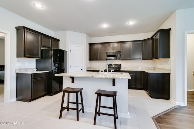 118 Barnet Ct, Lafayette, LA 70507 - kitchen with black appliances, a sink, a kitchen bar, dark brown cabinetry, and an island with sink
