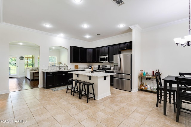 311 Victoria Lights Ln, Broussard, LA 70518 - kitchen with stainless steel appliances, dark cabinetry, arched walkways, a kitchen bar, and crown molding