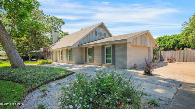113 Templeton Dr, Lafayette, LA 70508 - view of front of house with board and batten siding, brick siding, concrete driveway, a garage, and a chimney