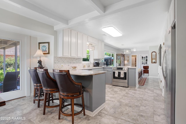 113 Templeton Dr, Lafayette, LA 70508 - kitchen featuring appliances with stainless steel finishes, a peninsula, beamed ceiling, light countertops, and tasteful backsplash