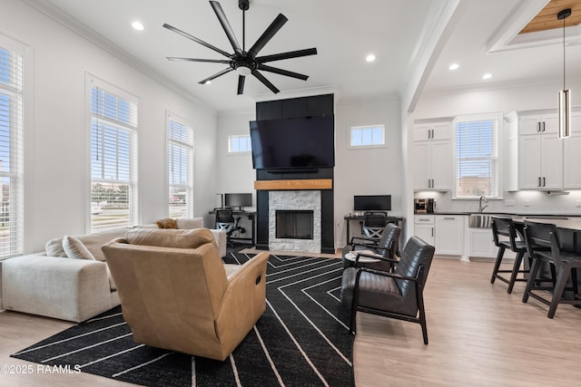 201 Lake Crest Ln, Youngsville, LA 70592 - living area with light wood-style floors, ornamental molding, a stone fireplace, recessed lighting, and a ceiling fan