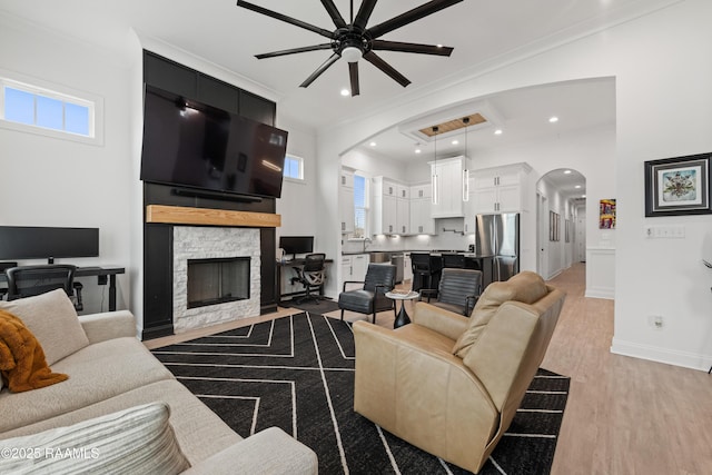 201 Lake Crest Ln, Youngsville, LA 70592 - living room with arched walkways, a ceiling fan, healthy amount of natural light, crown molding, and a stone fireplace