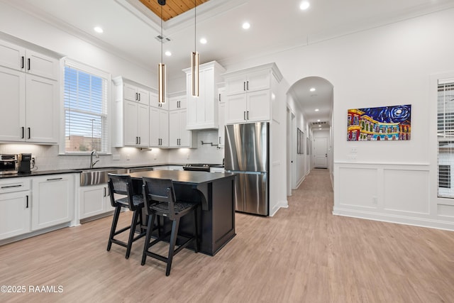 201 Lake Crest Ln, Youngsville, LA 70592 - kitchen featuring freestanding refrigerator, a sink, dark countertops, ornamental molding, and arched walkways