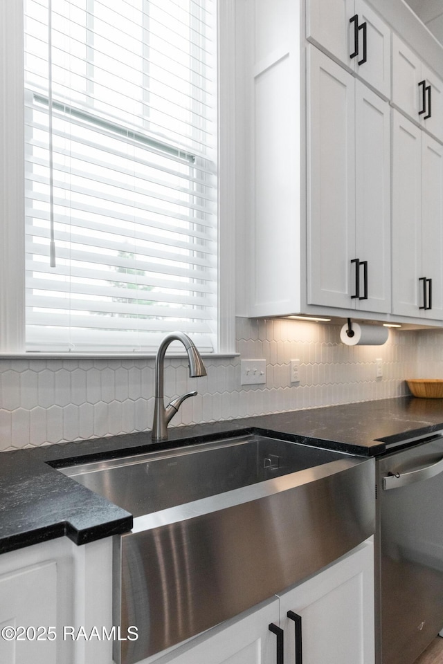 201 Lake Crest Ln, Youngsville, LA 70592 - kitchen with dark countertops, backsplash, dishwasher, a sink, and white cabinets