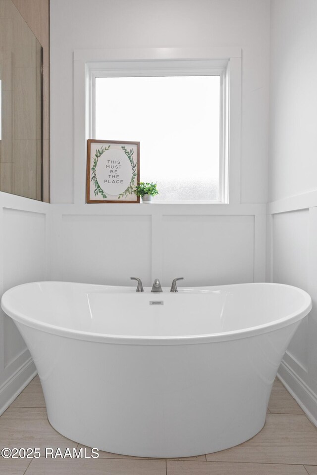 201 Lake Crest Ln, Youngsville, LA 70592 - full bathroom with a decorative wall, plenty of natural light, a freestanding tub, and a wainscoted wall