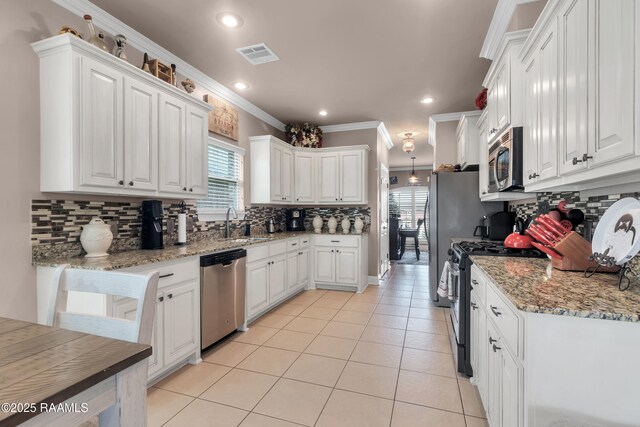 107 Ace Ln, Lafayette, LA 70506 - kitchen with appliances with stainless steel finishes, plenty of natural light, light tile patterned floors, white cabinets, and crown molding