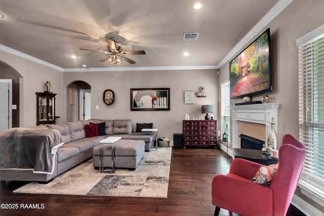 107 Ace Ln, Lafayette, LA 70506 - living area with arched walkways, ceiling fan, a tiled fireplace, dark wood-type flooring, and crown molding