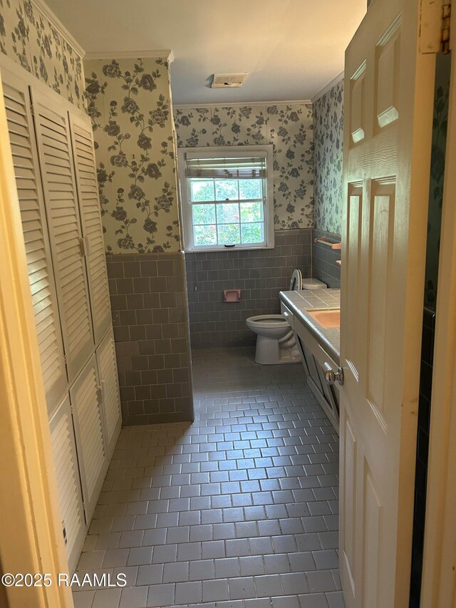 500 Brentwood Blvd, Lafayette, LA 70503 - bathroom featuring wallpapered walls, wainscoting, vanity, toilet, and tile walls