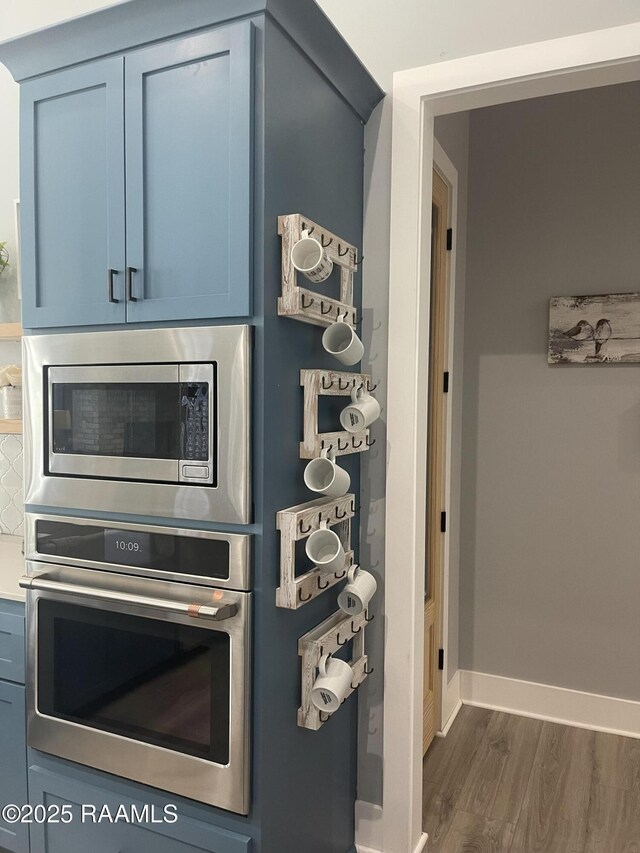 5087 Natali Rd, Lake Charles, LA 70607 - detailed view of stainless steel appliances, dark wood finished floors, baseboards, and blue cabinets
