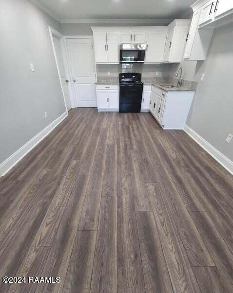 400 S Granger St, Erath, LA 70533 - kitchen with stainless steel microwave, range, dark wood-type flooring, baseboards, and white cabinetry
