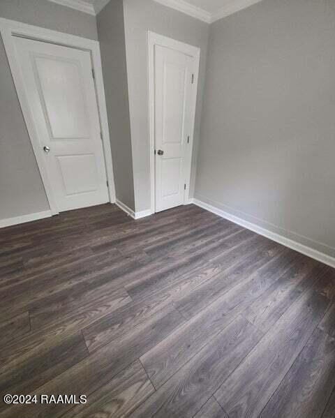 400 S Granger St, Erath, LA 70533 - unfurnished bedroom with crown molding, baseboards, and dark wood-style flooring