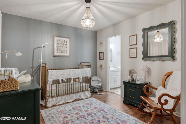 210 Long Plantation Blvd Unit C, Lafayette, LA 70508 - bedroom featuring wood finished floors, a crib, ensuite bathroom, and a chandelier