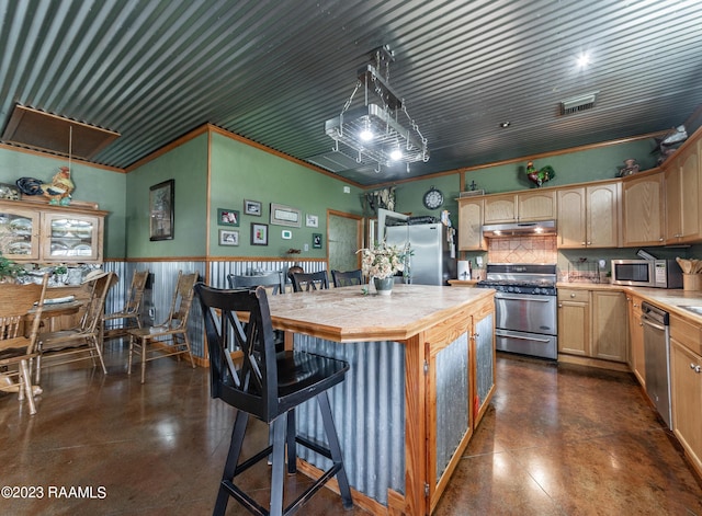 2944 Main Hwy, Breaux Bridge, LA 70517 - kitchen with appliances with stainless steel finishes, under cabinet range hood, a kitchen island, light brown cabinetry, and decorative backsplash