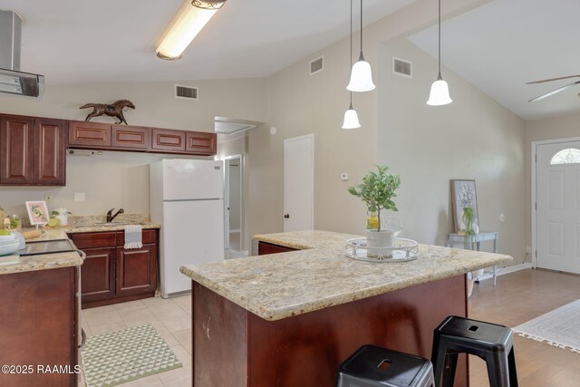 213 Marilyn Dr, Lafayette, LA 70503 - kitchen with freestanding refrigerator, a kitchen breakfast bar, a center island, high vaulted ceiling, and hanging light fixtures