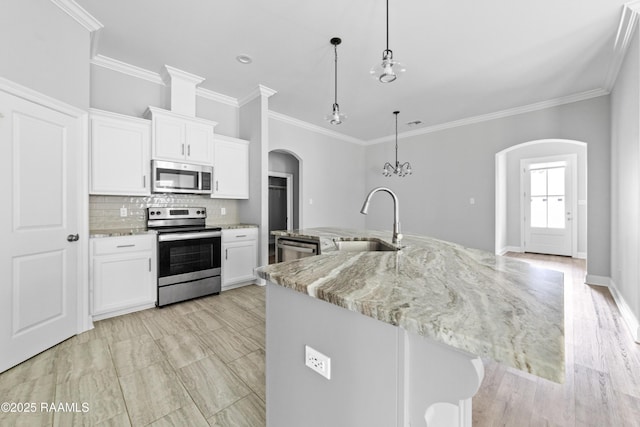 147 Gable Crest Dr, Lafayette, LA 70507 - kitchen featuring appliances with stainless steel finishes, arched walkways, tasteful backsplash, white cabinets, and a large island