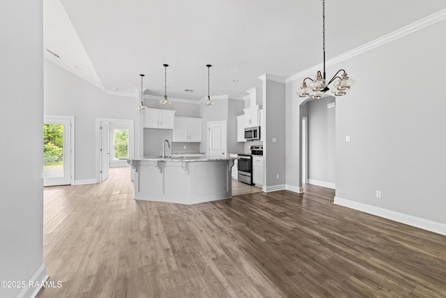 147 Gable Crest Dr, Lafayette, LA 70507 - kitchen with stainless steel appliances, a chandelier, light wood-style floors, a kitchen island with sink, and white cabinets