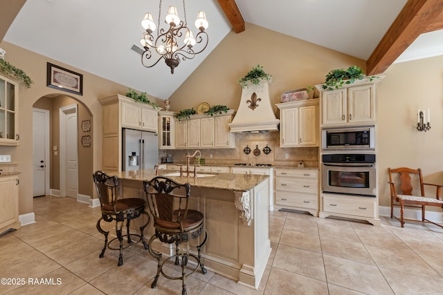 104 Baltimore Ln, Lafayette, LA 70506 - kitchen featuring appliances with stainless steel finishes, arched walkways, beam ceiling, light stone counters, and decorative backsplash