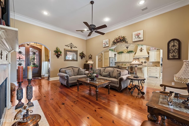 104 Baltimore Ln, Lafayette, LA 70506 - living room with arched walkways, ceiling fan, a fireplace, ornamental molding, and light wood-style flooring