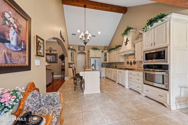 104 Baltimore Ln, Lafayette, LA 70506 - kitchen featuring appliances with stainless steel finishes, cream cabinets, backsplash, arched walkways, and beamed ceiling