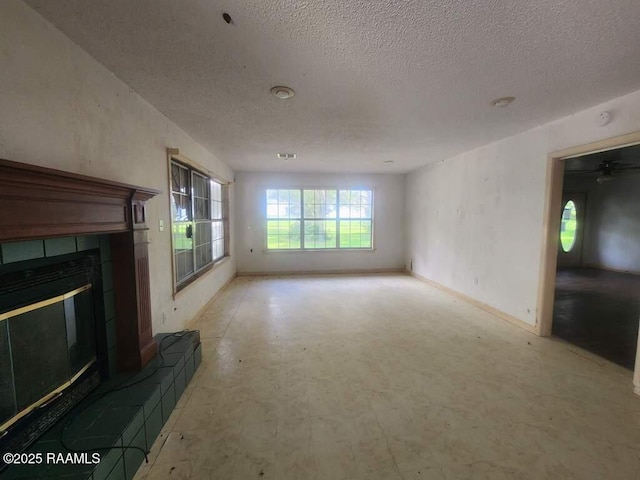 37208 Monceaux Rd, Gueydan, LA 70542 - unfurnished living room with a textured ceiling, a tiled fireplace, and baseboards