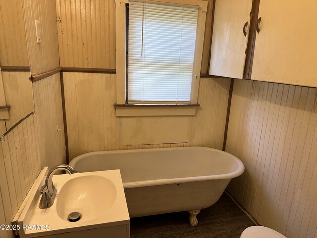 1002 Vidrine St, Opelousas, LA 70570 - full bathroom featuring a sink, a freestanding bath, wood walls, and wood finished floors