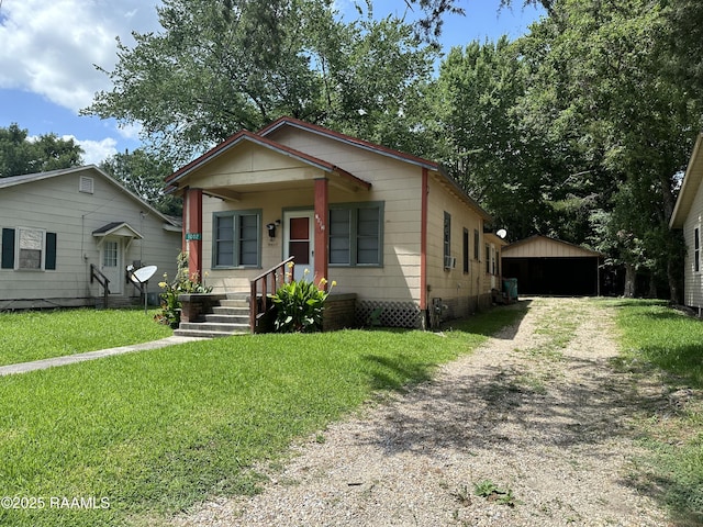 1002 Vidrine St, Opelousas, LA 70570 - bungalow-style house featuring a front yard, driveway, covered porch, an outdoor structure, and a detached garage