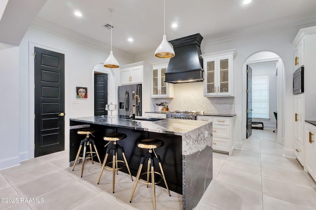 307 Harvest Creek Ln, Lafayette, LA 70508 - kitchen featuring custom exhaust hood, arched walkways, appliances with stainless steel finishes, backsplash, and an island with sink