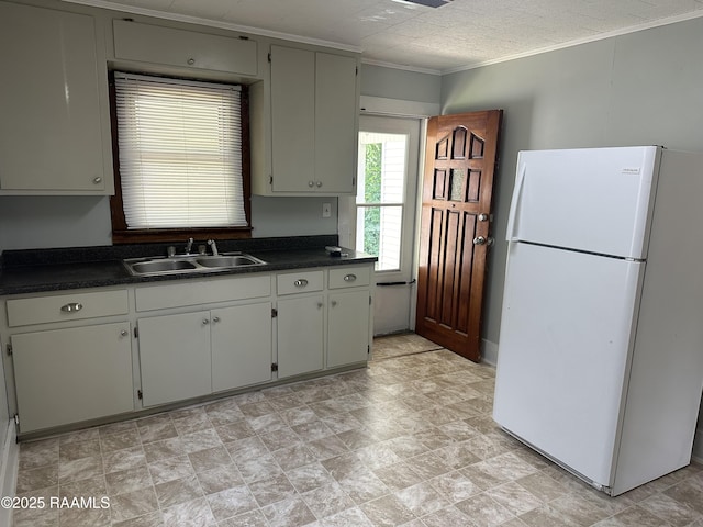 627 S Railroad Ave, Opelousas, LA 70570 - kitchen with freestanding refrigerator, a sink, dark countertops, ornamental molding, and stone finish flooring