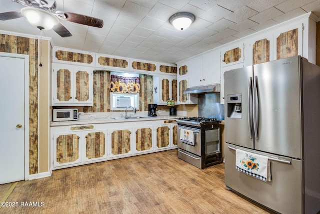 1521 Saint Jude Ave, New Iberia, LA 70560 - kitchen featuring appliances with stainless steel finishes, light countertops, under cabinet range hood, white cabinets, and a ceiling fan