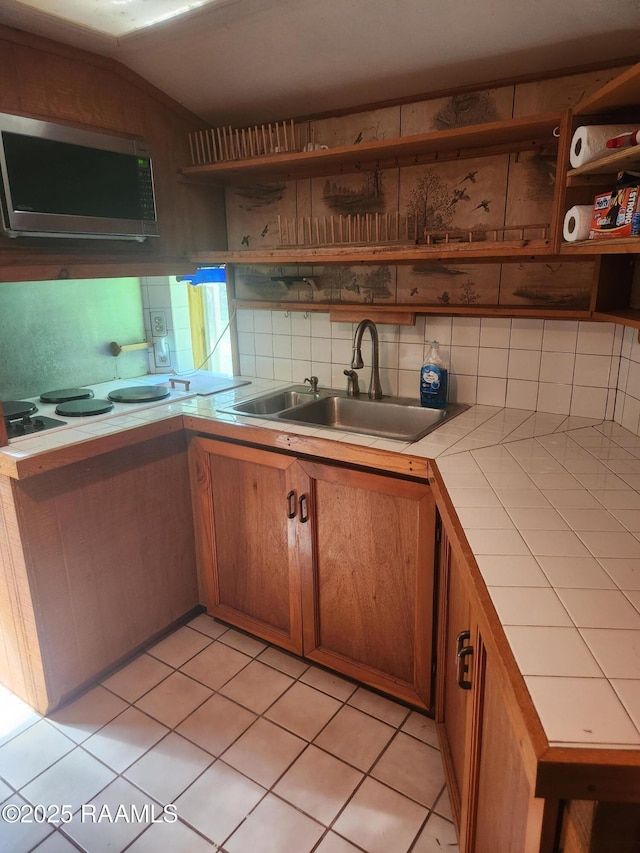 101 Hidden Hills Lake Rd, Arnaudville, LA 70512 - kitchen with stainless steel microwave, tile counters, open shelves, brown cabinetry, and light tile patterned flooring