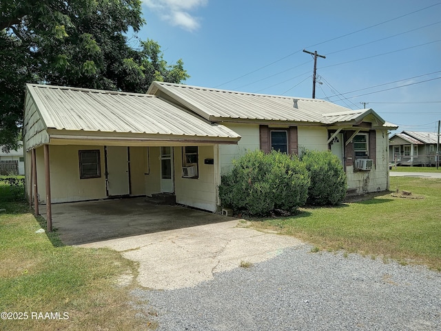 1502 Cherokee St, Abbeville, LA 70510 - view of front facade featuring cooling unit, driveway, a front yard, metal roof, and an attached carport
