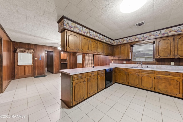 1530 S Fieldspan Rd, Duson, LA 70529 - kitchen featuring black dishwasher, a peninsula, light countertops, brown cabinets, and wooden walls