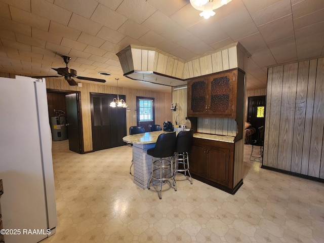 2115 Vige St, Opelousas, LA 70570 - kitchen with freestanding refrigerator, light flooring, wood walls, light countertops, and a peninsula