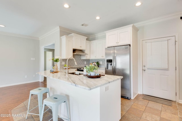 117 Fawn Ln, Broussard, LA 70518 - kitchen featuring stainless steel fridge with ice dispenser, under cabinet range hood, ornamental molding, a breakfast bar area, and light stone counters