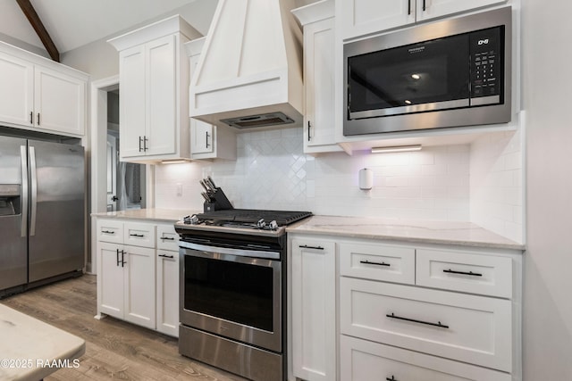236 Whispering Meadows Rd, Broussard, LA 70518 - kitchen featuring appliances with stainless steel finishes, custom exhaust hood, wood finished floors, white cabinetry, and vaulted ceiling