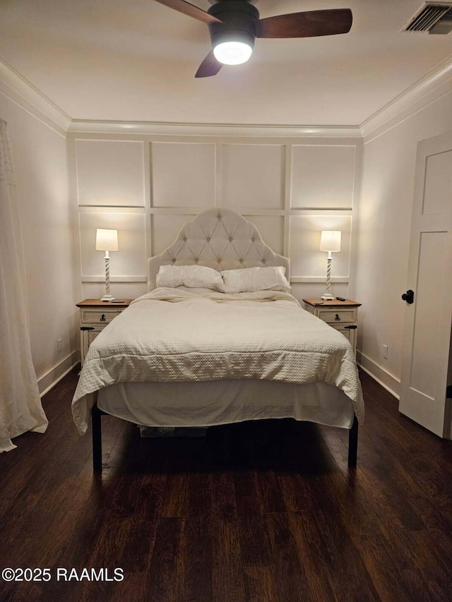 bedroom with wood finished floors, ornamental molding, ceiling fan, and a decorative wall