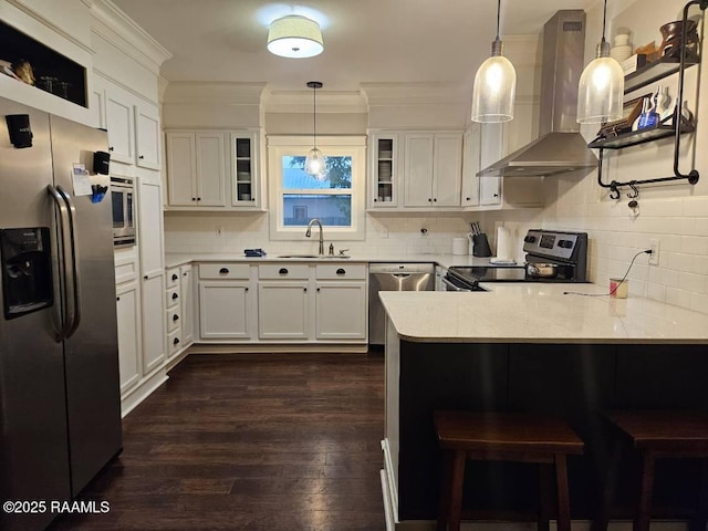kitchen featuring appliances with stainless steel finishes, island range hood, a peninsula, glass insert cabinets, and decorative backsplash