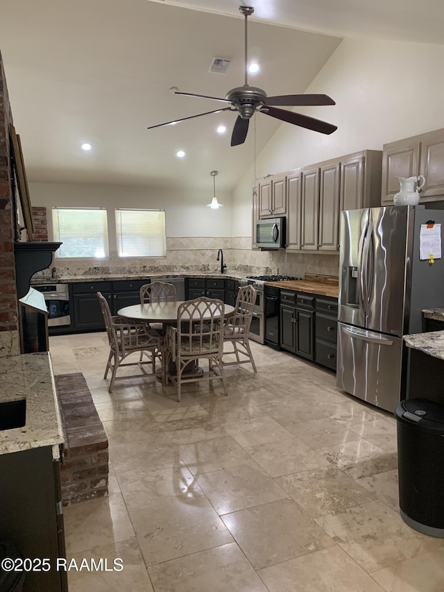 1921 E Willow St, Lafayette, LA 70501 - kitchen with stainless steel appliances, a ceiling fan, light stone countertops, backsplash, and high vaulted ceiling