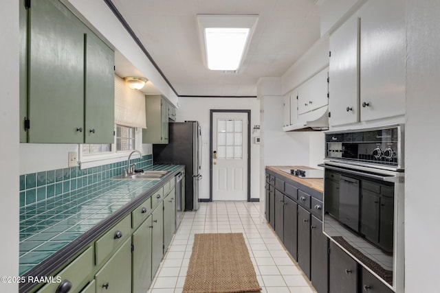 301 Broadmoor Blvd, Lafayette, LA 70503 - kitchen with appliances with stainless steel finishes, tile counters, under cabinet range hood, green cabinetry, and light tile patterned flooring