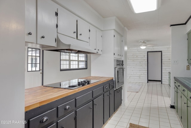 301 Broadmoor Blvd, Lafayette, LA 70503 - kitchen featuring under cabinet range hood, stainless steel oven, light tile patterned floors, butcher block counters, and black electric cooktop