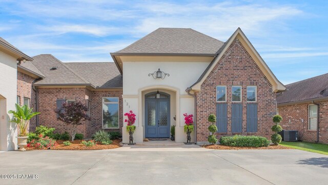 121 Snapping Ln, Broussard, LA 70518 - view of exterior entry with french doors, brick siding, roof with shingles, and stucco siding