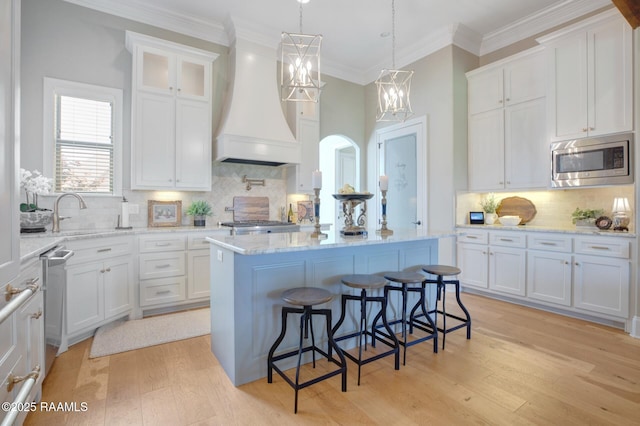 121 Snapping Ln, Broussard, LA 70518 - kitchen featuring appliances with stainless steel finishes, custom range hood, a kitchen island, white cabinetry, and crown molding