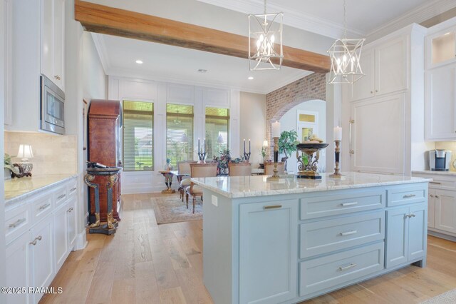 121 Snapping Ln, Broussard, LA 70518 - kitchen featuring stainless steel microwave, white cabinetry, light wood finished floors, arched walkways, and tasteful backsplash