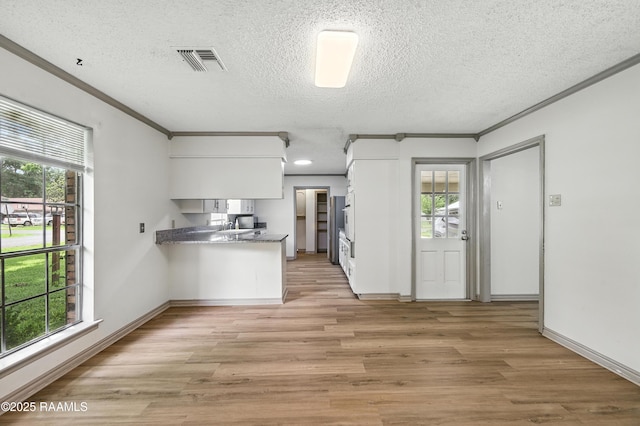 301 Estainville Ave, Lafayette, LA 70508 - kitchen featuring ornamental molding, white cabinets, light wood-style flooring, plenty of natural light, and a textured ceiling