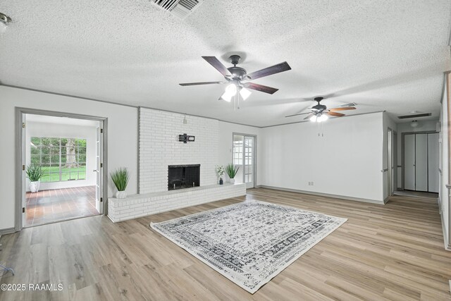 301 Estainville Ave, Lafayette, LA 70508 - living room featuring ceiling fan, a textured ceiling, light wood-style flooring, and a fireplace