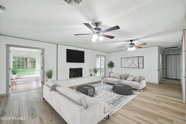 301 Estainville Ave, Lafayette, LA 70508 - living area featuring a textured ceiling, light wood-type flooring, a ceiling fan, and a brick fireplace